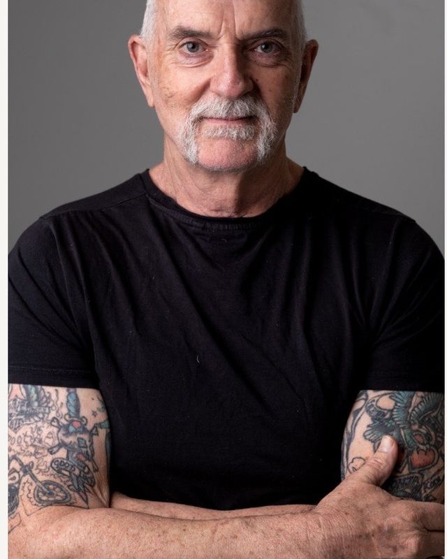 Andy McPhee in a black t-shirt folding his arms.